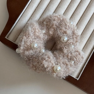 Gros plan sur le chouchou en peluche beige orné de perles blanches élégantes