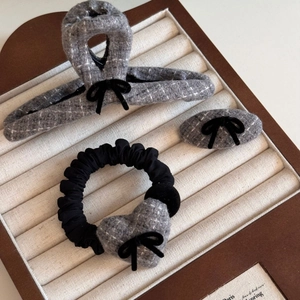 Close-up of gray tweed hair clip set with black velvet bow and fabric texture