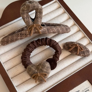 Detail of tweed bow hair clips and scrunchie set in brown plaid for autumn winter styles