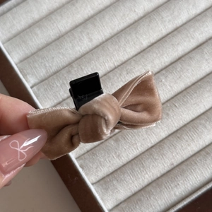 Detail shot of a handmade champagne velvet bow hair clip held by hand showing texture