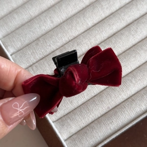 Detail of a burgundy velvet bow hair claw clip showing soft texture and grip