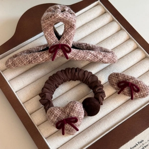 Close-up of brown tweed hair accessories with red velvet bows on a beige jewelry display