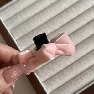 Close-up of a pink velvet bow hair claw clip with soft texture on a hand display
