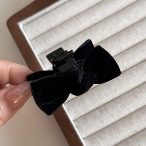 Detail of small black velvet bow hair claw clip showing texture and secure grip