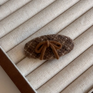 Detailed macro view of the brown tweed fabric texture on an oval-shaped hair clip