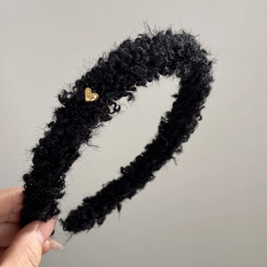Gros plan d'un serre-tête en peluche noire avec un petit pendentif en forme de cœur doré