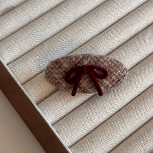 Detailed view of the vintage plaid wool hair clip with a red flocked bow accent
