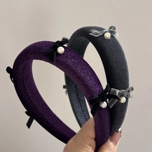 Detail of velvet padded headband with bow and pearl accents in purple and grey