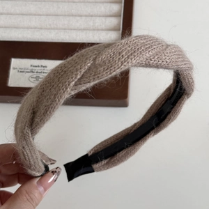 Dettaglio della fascia in maglia a trecce beige con design intrecciato e morbido