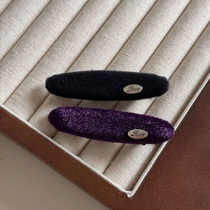 Detailed view of elegant velvet oval hair clips in black and purple with silver Love tag
