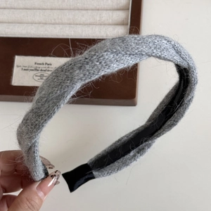 Dettaglio della fascia in maglia grigia con design a incrocio e morbida trama in peluche