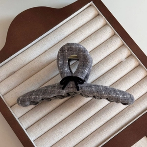 Close-up of grey plaid tweed hair claw clip with a black velvet bow on jewelry tray