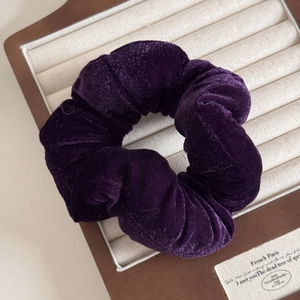 Detailed close-up of dark purple velvet scrunchie showing soft texture and pleated design