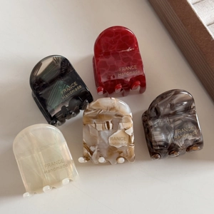 Détail de cinq petites pinces à cheveux en acide acétique aux textures de marbre variées