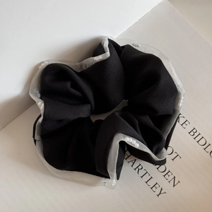 Detailed close-up of a black mesh scrunchie with cream lace edges and small white pearls