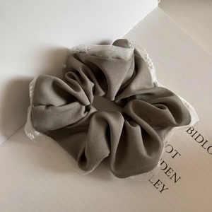 Detail showing grey fabric scrunchie with white mesh edging and pearl embellishments