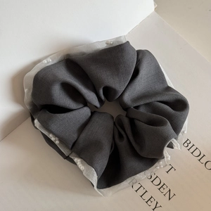 Detail of grey fabric scrunchie with white organza ruffle edge and pearl embellishments