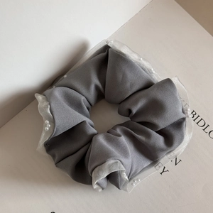 Detail of grey fabric scrunchie with white organza mesh edge and pearl embellishments