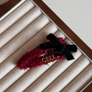Close-up of a red tweed hair clip featuring a black velvet bow and golden metal letters