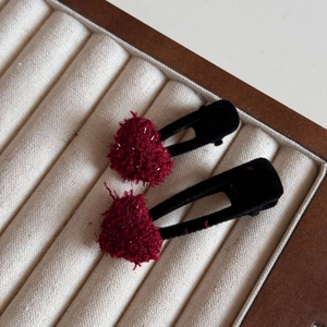 Close-up of dual red plush heart hair clips with black flocked duckbill base in box