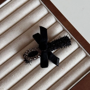 Detailed view of a black velvet bow hair clip with plush texture and decorative bead
