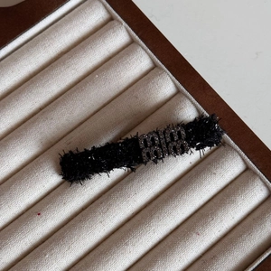 Macro shot of black velvet hair clip with rhinestone letter detailing and subtle shimmer