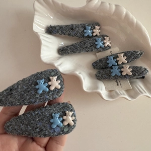 Close-up of gray tweed fabric hair clips with cute blue and beige resin bears