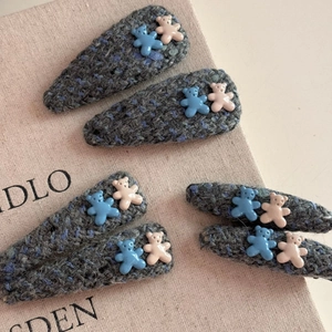 Close-up of knit fabric texture on blue hair clips with cute resin bear accents