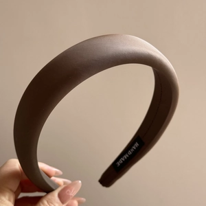 Macro shot of brown satin padded headband with a handmade label and smooth texture