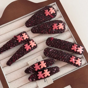 Detailed view of 8 purple tweed hair clips with pink resin bear accents on beige display
