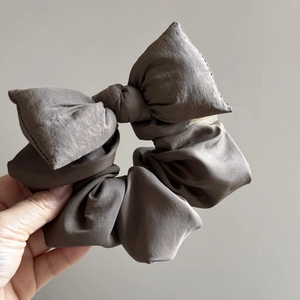 Macro shot of large dark grey bow scrunchie showing fabric texture and pleated detail
