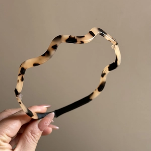 Detailed view of wave-shaped tortoiseshell headband with a glossy leopard pattern texture