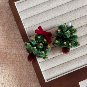 Detailed macro of handmade Christmas tree hair clips with green plush and red velvet bow