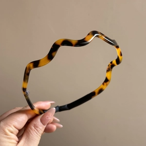 Detail showing the wavy acetate headband with tortoise shell pattern and non-slip tips