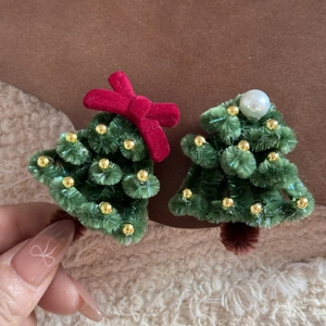 Detailed view of handmade green pipe cleaner Christmas tree hair clips with velvet bows