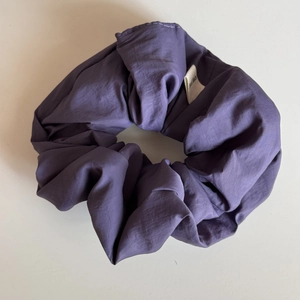 Detailed close-up of a handmade purple fabric scrunchie showing stitching and material texture