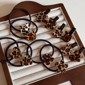 Detailed macro view of leopard print acetate hair clips with inlaid rhinestones and gold text