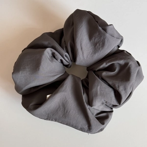 Detail view of large charcoal gray scrunchie with matte woven fabric and brand label
