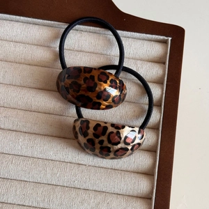 Close-up of leopard print hair ties with high-gloss finish on a beige jewelry tray