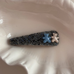 Detail of knitted grey hair clip featuring cute blue and beige resin bear charms