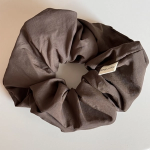Detail of coffee brown oversized scrunchie with pleated texture and Hand Made label