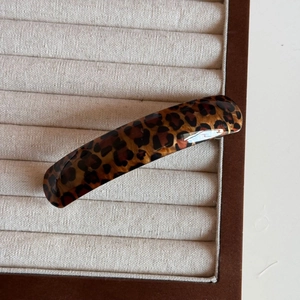 Close-up of a leopard print hair clip in polished acetate on a white jewelry tray