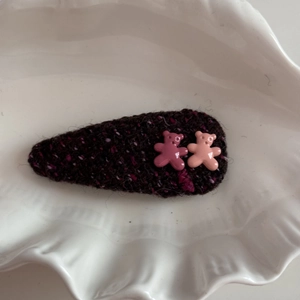 Close-up of a tweed fabric hair clip with two cute plastic bear charms on a white tray