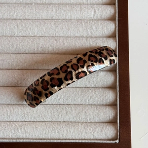 Detail of elegant leopard print hair clip in brown and black on a white velvet tray