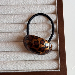 Detail of high-elastic black hair tie with polished leopard print resin ornament