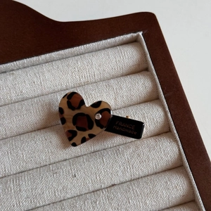 Detail of handmade leopard heart hair clip with crystal on a linen jewelry tray