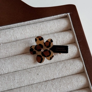 Close-up of leopard print acetate flower hair clip with rhinestone and gold branding