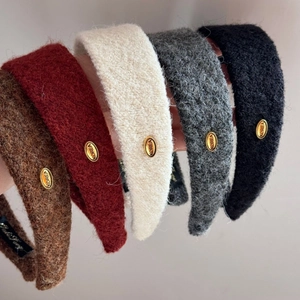 Détail de serre-têtes en peluche montrant la texture douce et le logo doré en métal