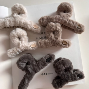 Détail montrant la texture pelucheuse et le logo ovale sur les pinces à cheveux