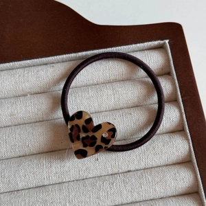 Close-up of leopard print heart hair tie with small diamond on linen display tray